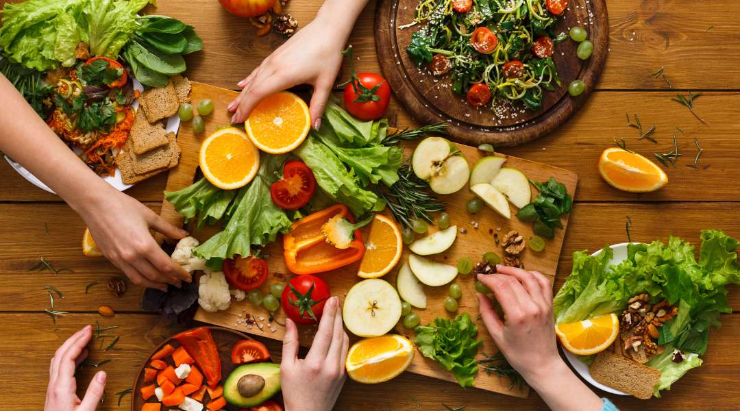 Hände greifen nach Früchte, Gemüse und anderen pflanzlichen Lebensmitteln